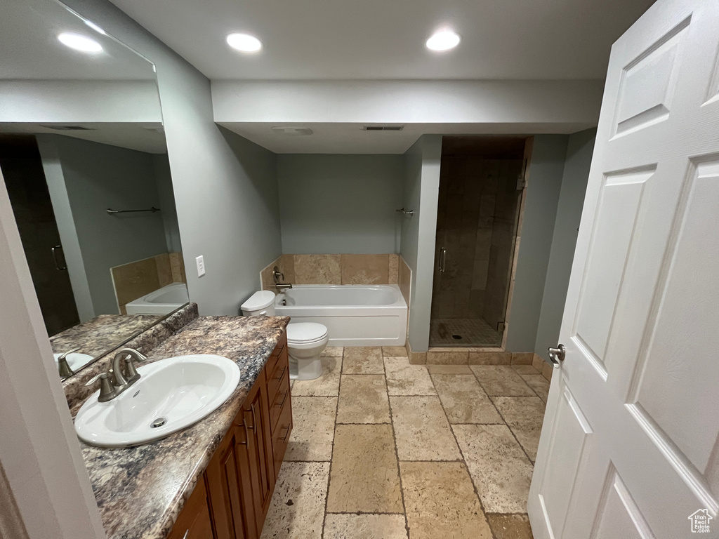 Bathroom featuring stone tile flooring, a bath, vanity, a shower stall, and recessed lighting