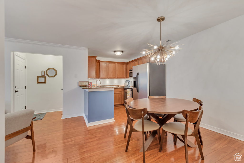 Dining room with a chandelier, light wood-style floors, and crown molding