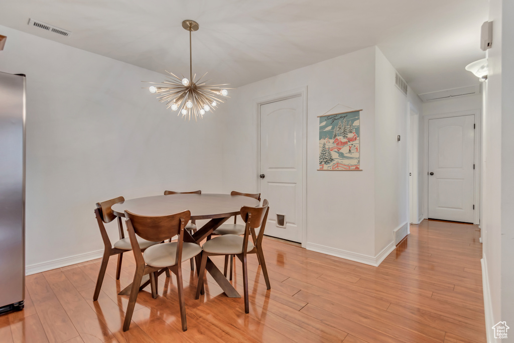 Dining area with light wood-style flooring and a chandelier