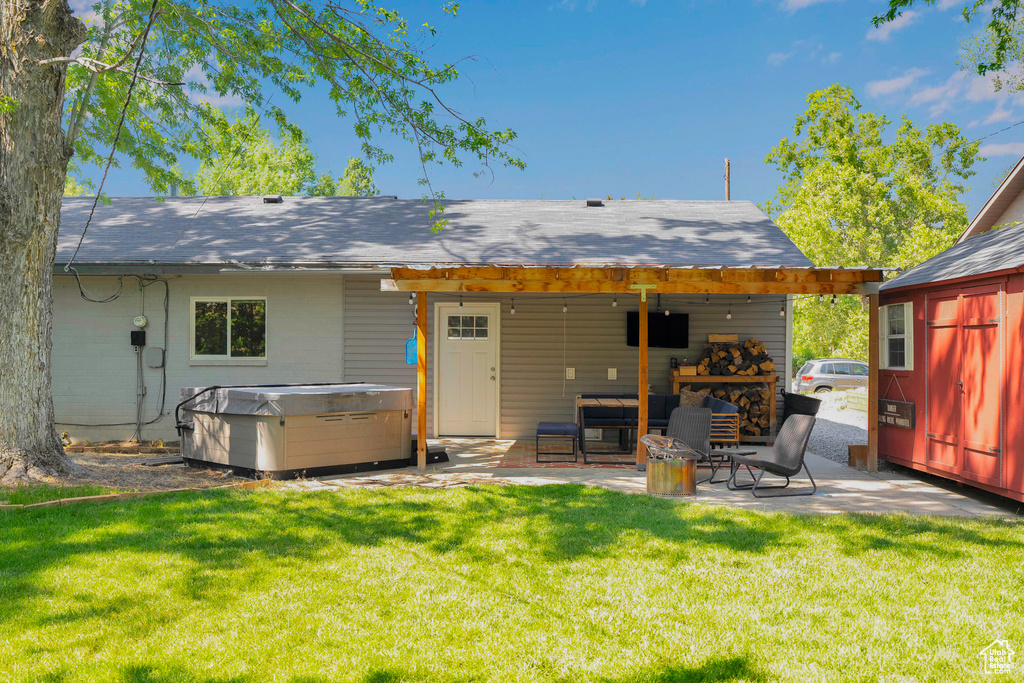 Back of house featuring a hot tub, a patio area, and a yard