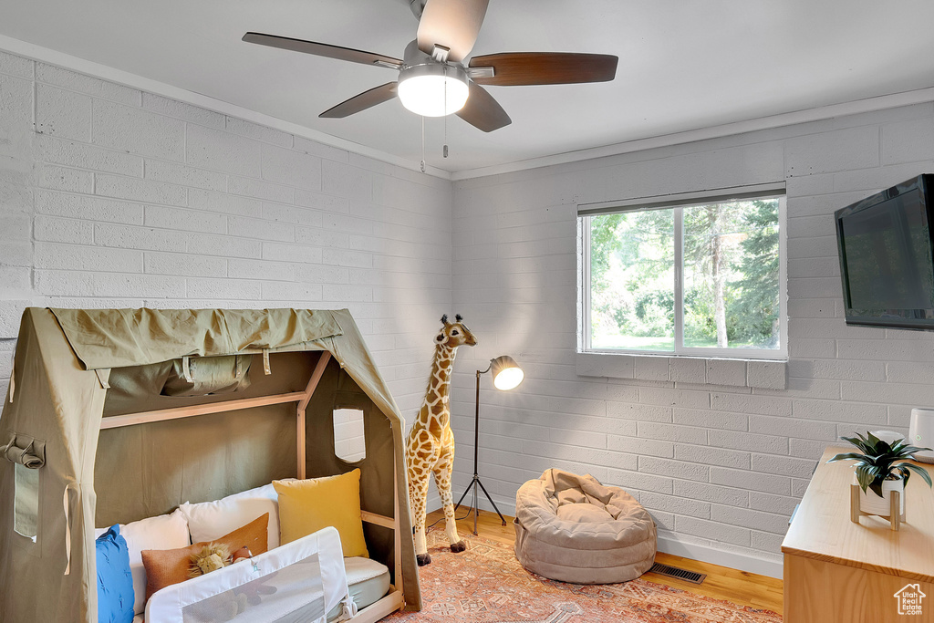 Bedroom featuring light wood finished floors, ornamental molding, and a ceiling fan