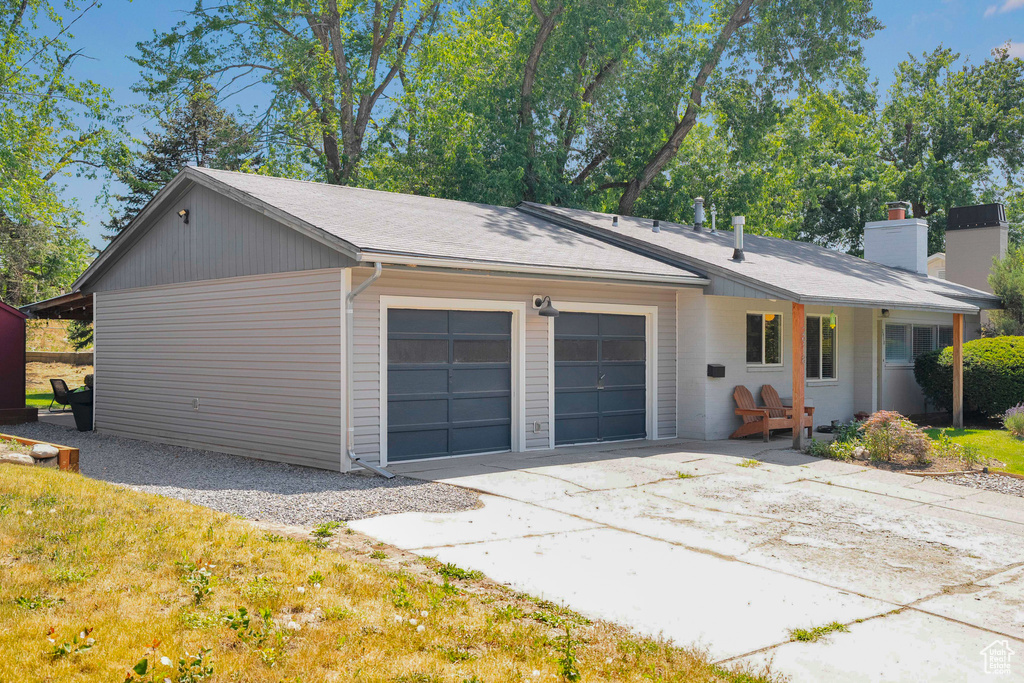 View of front of house featuring a chimney, a garage, a shingled roof, and concrete driveway