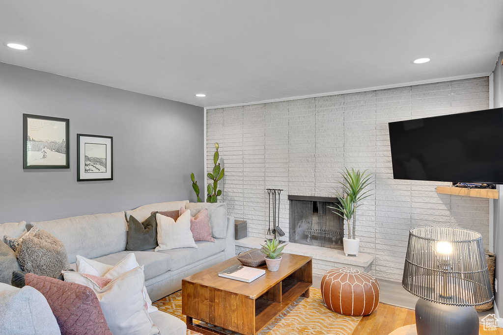 Living room with recessed lighting, a brick fireplace, and wood finished floors