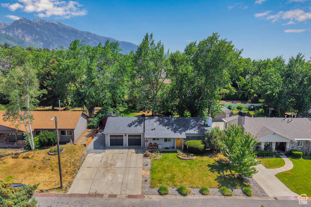 View of front of home with a garage, driveway, a front yard, and a mountain view
