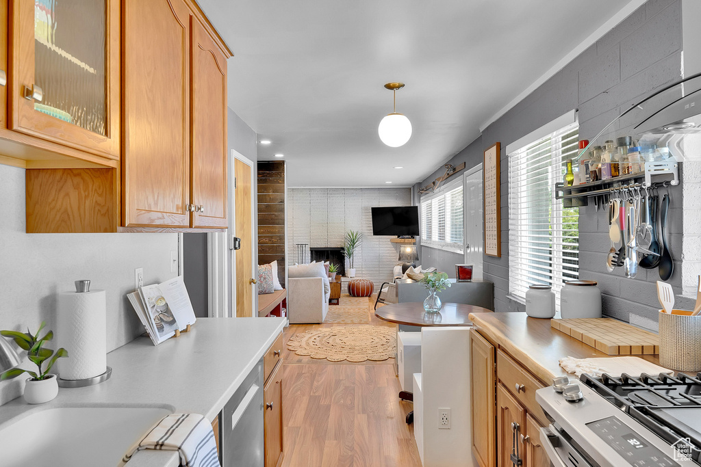 Kitchen with light wood finished floors, light countertops, glass insert cabinets, and stainless steel gas range