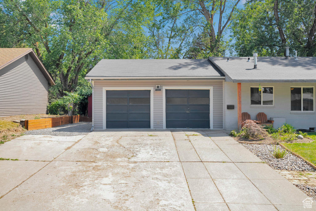 View of front facade with concrete driveway, a garage, and roof with shingles