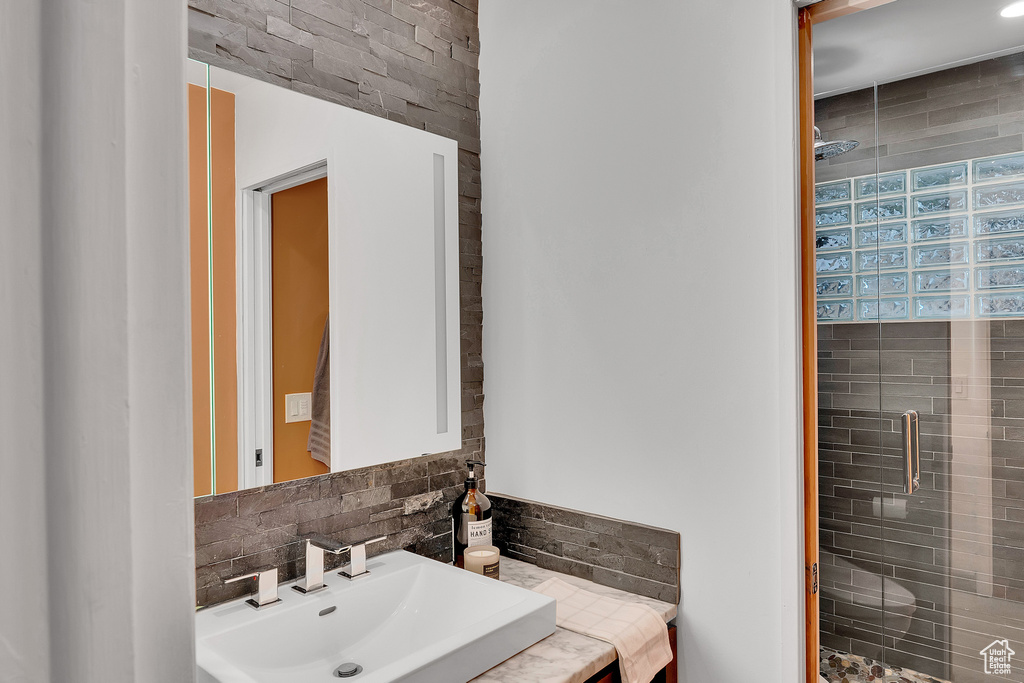 Full bath with a shower stall, decorative backsplash, and vanity