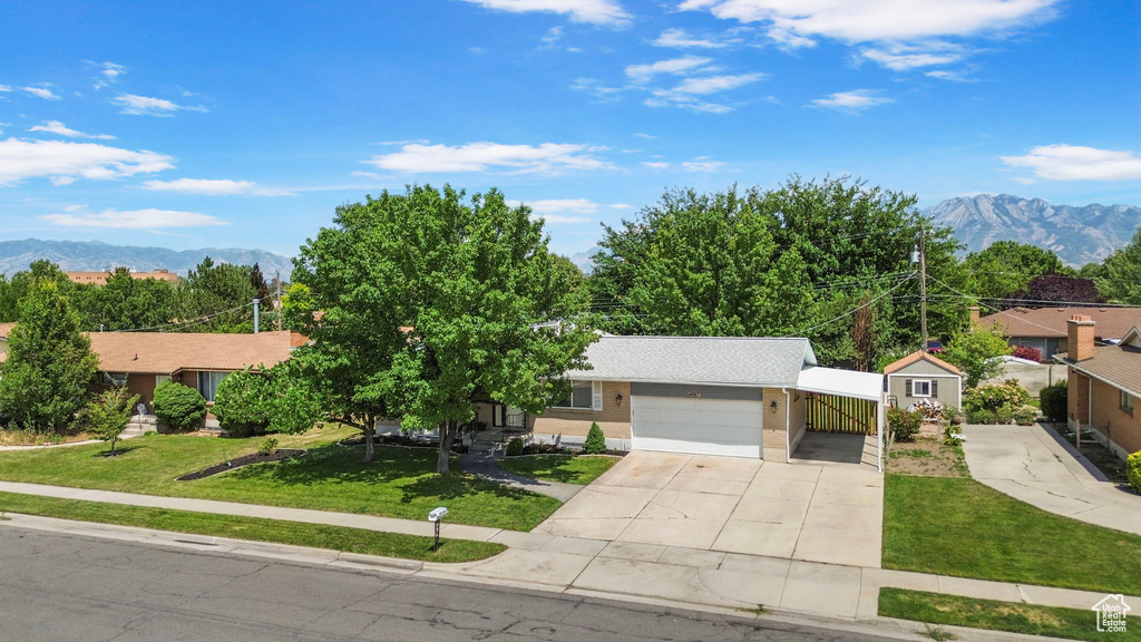 View of front of home with a front lawn, concrete driveway, a mountain view, and an attached garage