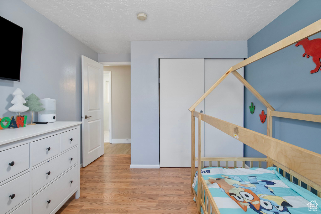 Bedroom featuring light wood finished floors, a textured ceiling, and a closet