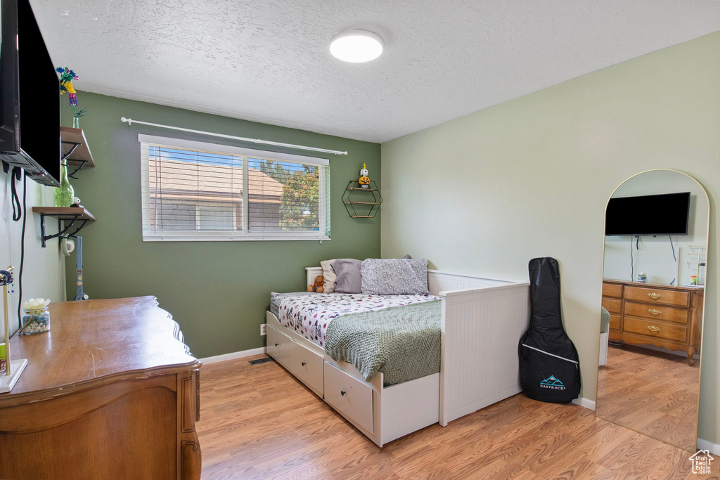 Bedroom with light wood finished floors and a textured ceiling