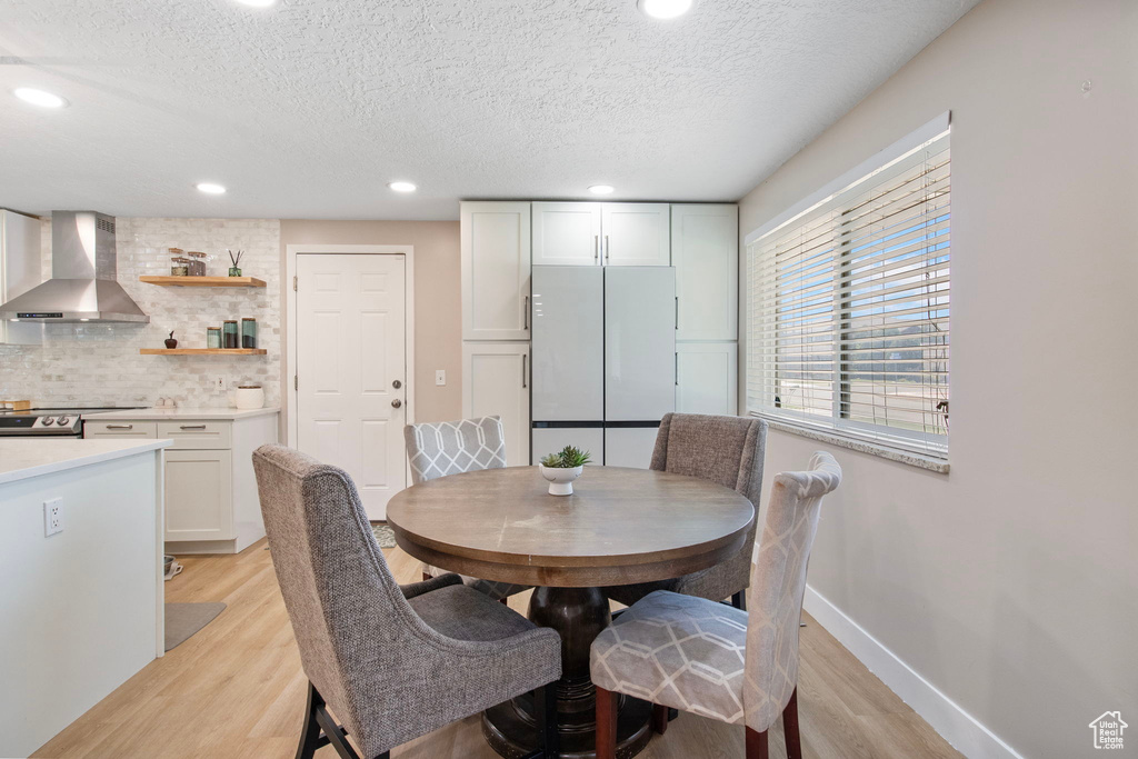 Dining room with light wood-style floors, a textured ceiling, and recessed lighting