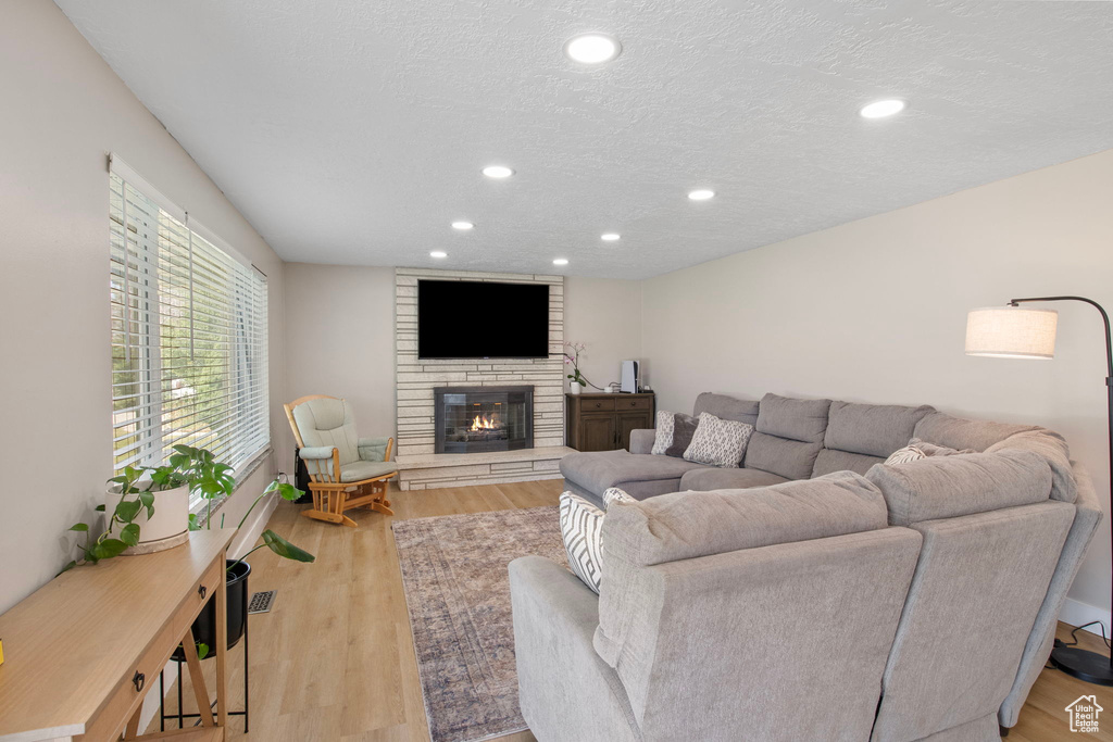 Living area with recessed lighting, a large fireplace, wood finished floors, and a textured ceiling