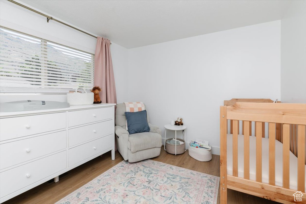Bedroom featuring wood finished floors and a nursery area