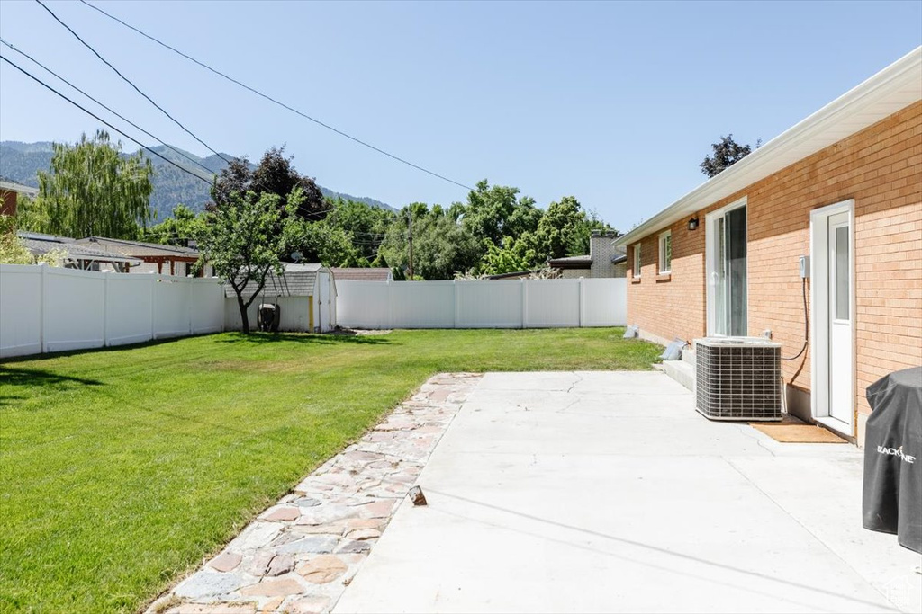 Fenced backyard with a patio area, a storage shed, and a mountain view