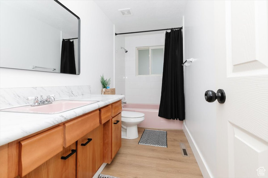 Bathroom featuring vanity, wood finished floors, and shower / bath combo with shower curtain