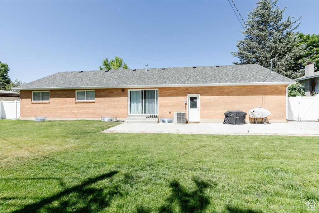 Rear view of property with brick siding, a patio area, and roof with shingles