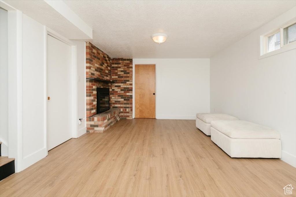 Unfurnished room featuring wood finished floors, a fireplace, and a textured ceiling