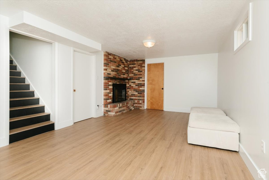 Unfurnished room featuring wood finished floors, stairs, a fireplace, and a textured ceiling