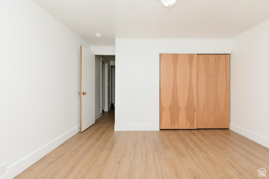 Unfurnished bedroom featuring light wood-style floors and a closet