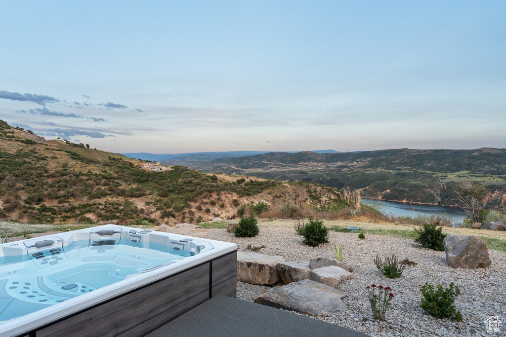 View of pool with a hot tub and a water and mountain view