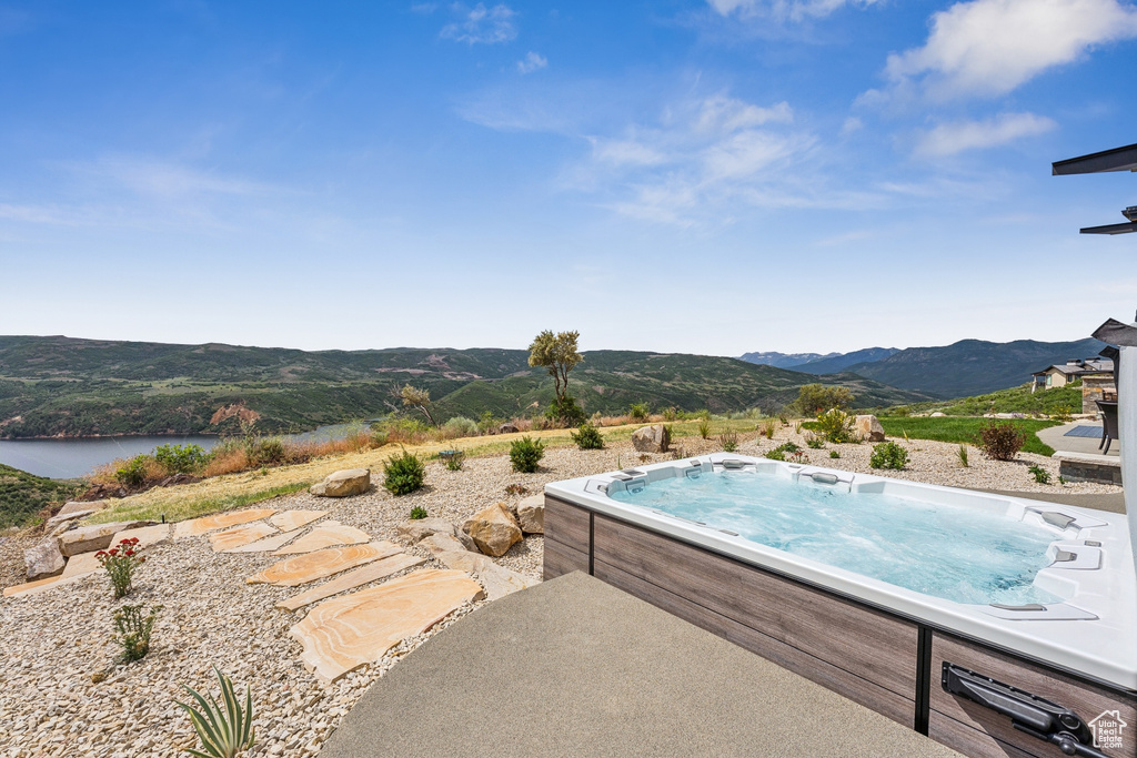 View of pool with a hot tub and a water and mountain view
