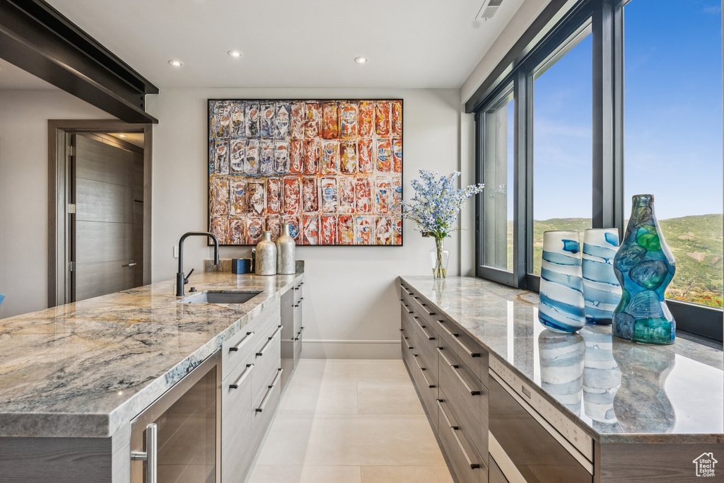 Kitchen featuring beverage cooler, recessed lighting, light stone counters, white cabinets, and a peninsula