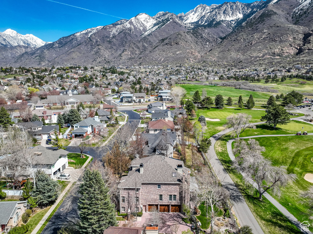 Aerial overview of property's location with a local golf course, a mountainous background, and nearby suburban area