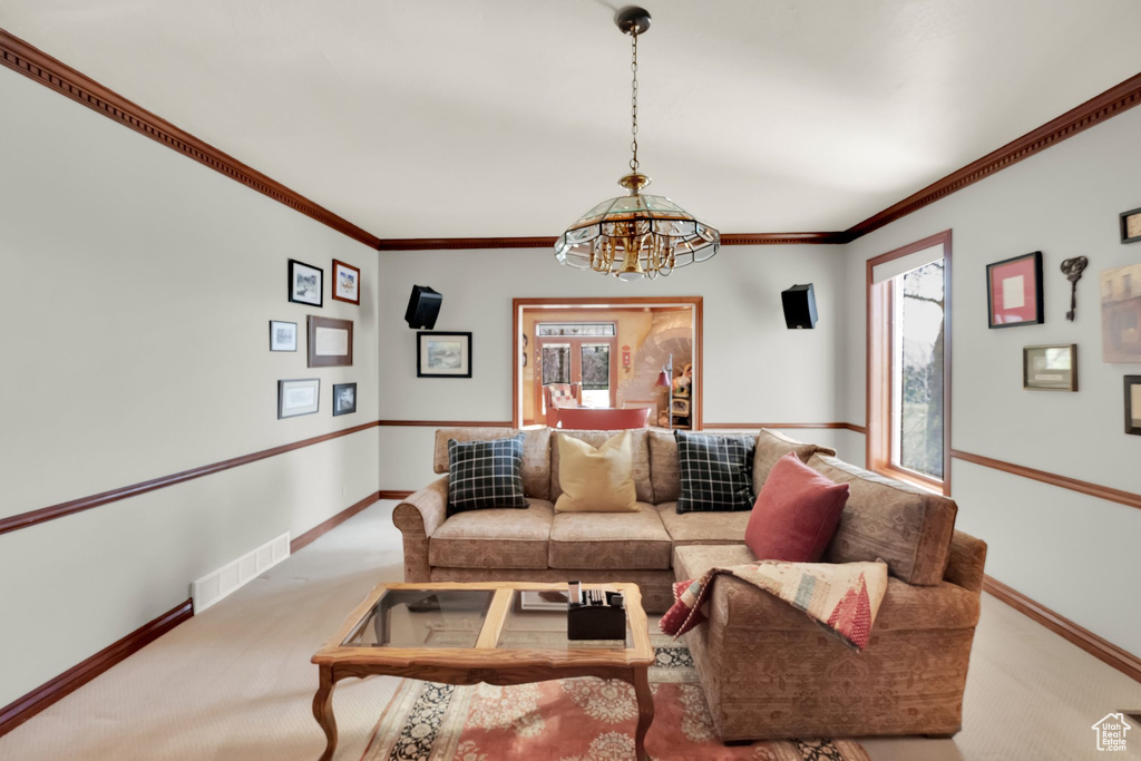 Living room featuring carpet floors, a chandelier, and crown molding