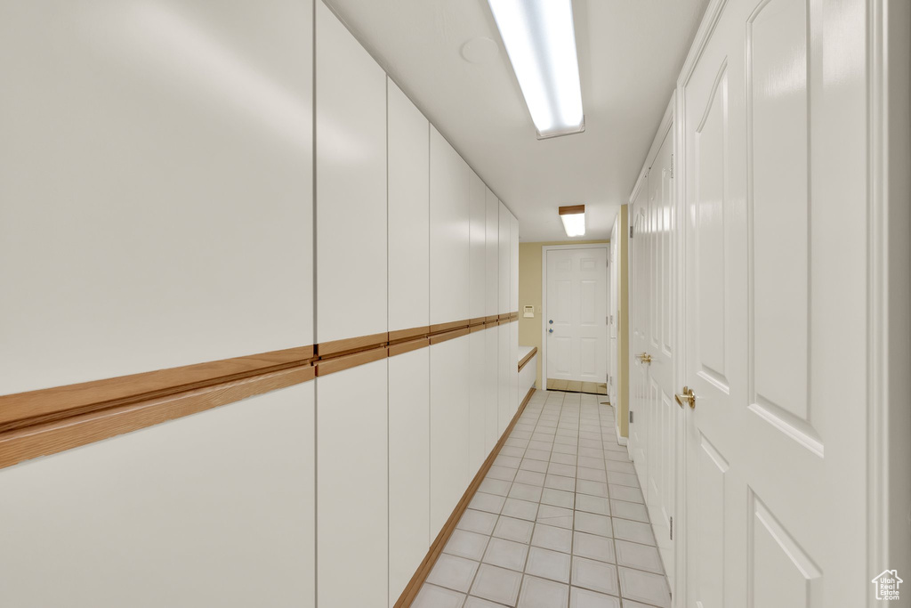 Hall with light tile patterned flooring and baseboards