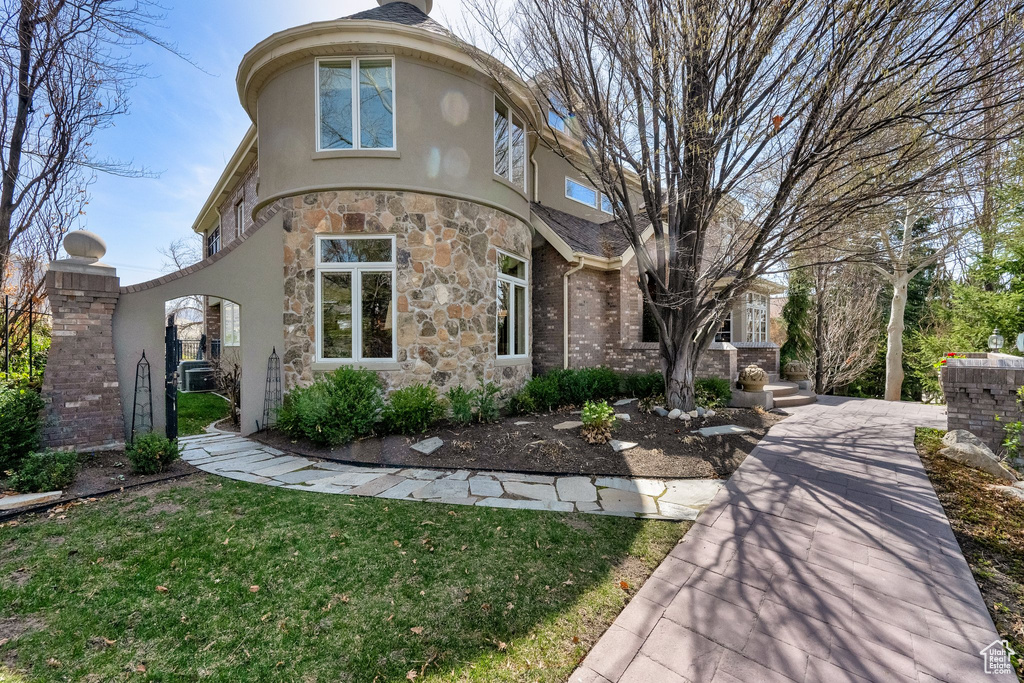 View of front of home featuring stone siding, stucco siding, and a front yard