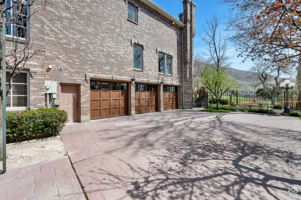 View of side of property with driveway, a garage, brick siding, and a mountain view