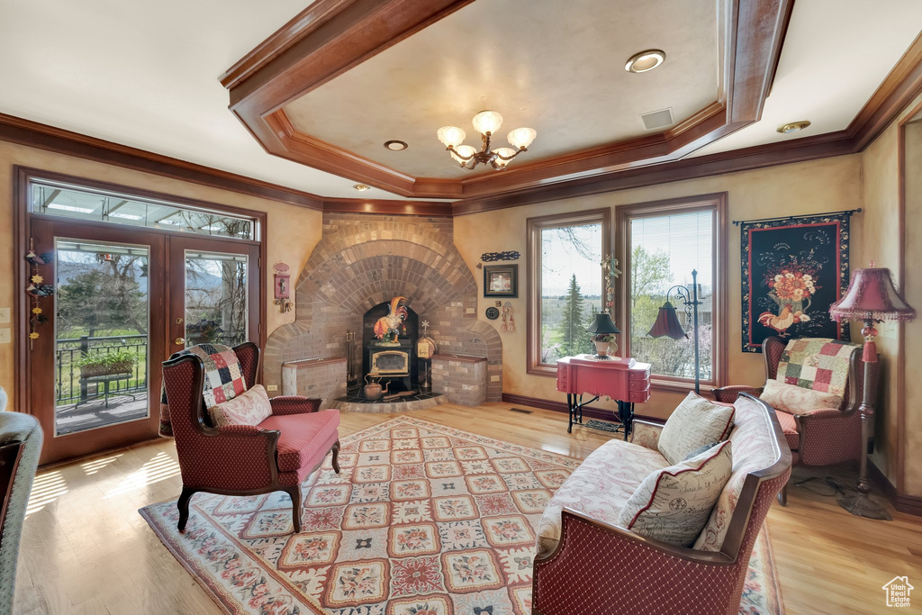 Living room with french doors, crown molding, a raised ceiling, and wood finished floors