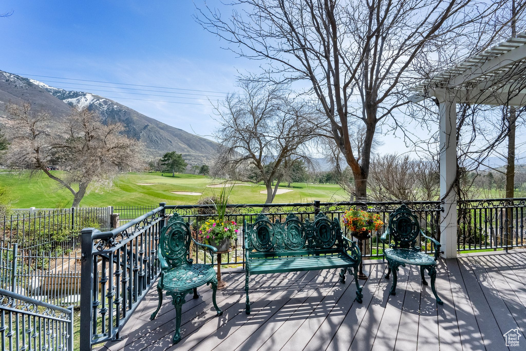 Wooden terrace with a mountain view, view of golf course, and a pergola