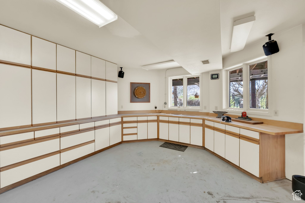 Kitchen featuring concrete floors, white cabinets, and light countertops