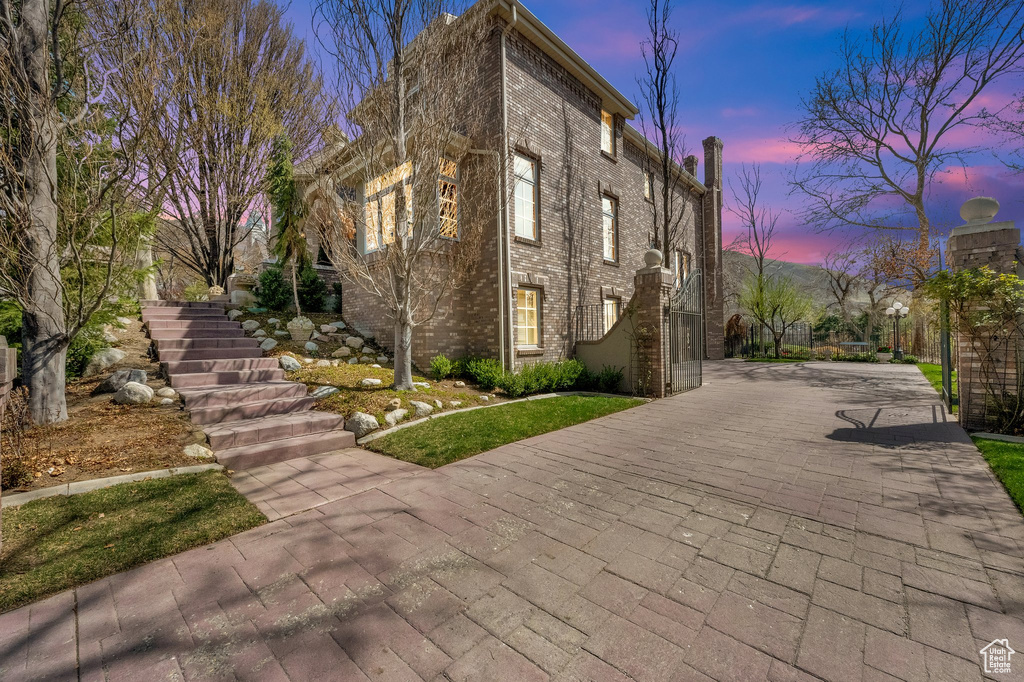 View of front of home featuring stairway, brick siding, and driveway