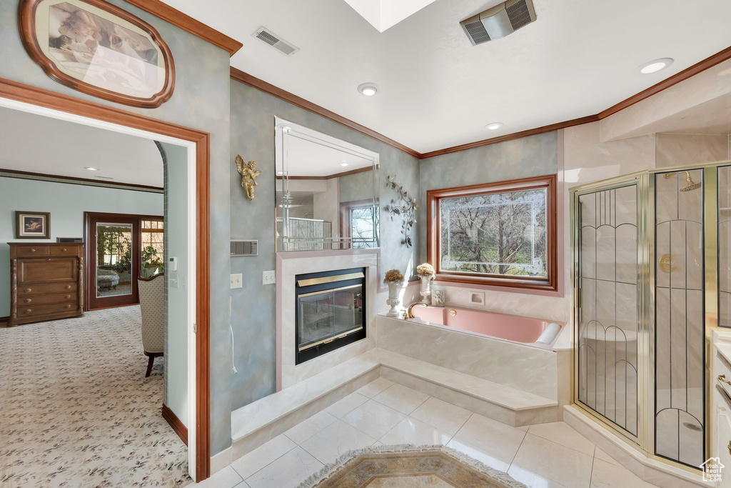 Bathroom featuring a glass covered fireplace, ornamental molding, healthy amount of natural light, a garden tub, and a stall shower