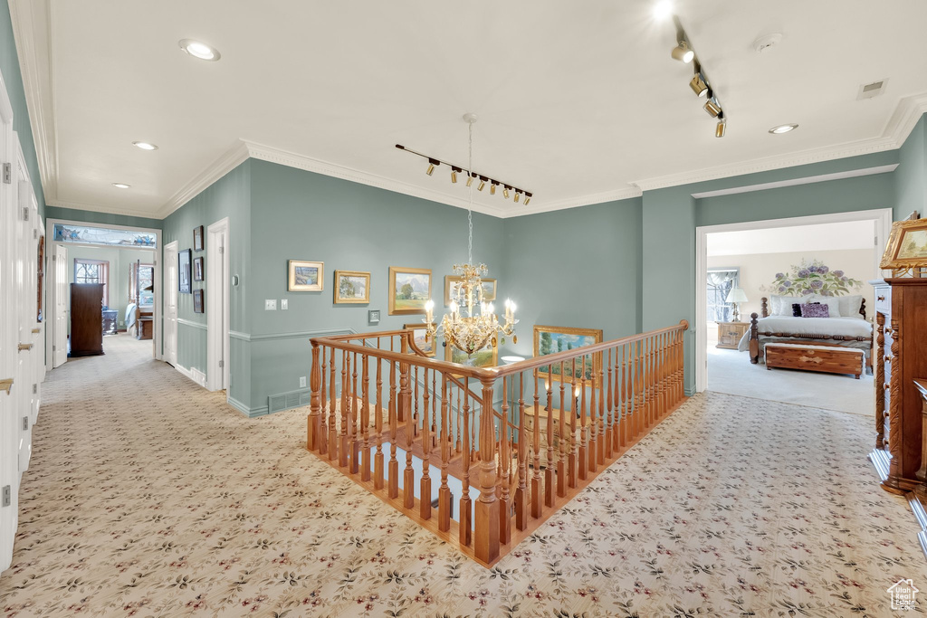 Hallway featuring carpet flooring, an upstairs landing, track lighting, ornamental molding, and recessed lighting