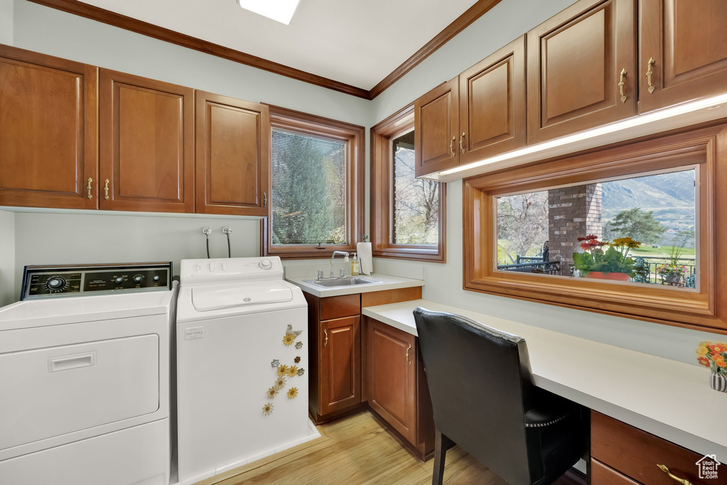 Laundry area with cabinet space, washing machine and clothes dryer, light wood-style floors, crown molding, and a desk