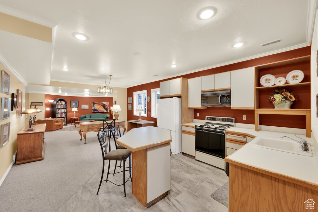Kitchen featuring white appliances, light countertops, a breakfast bar area, a kitchen island, and crown molding