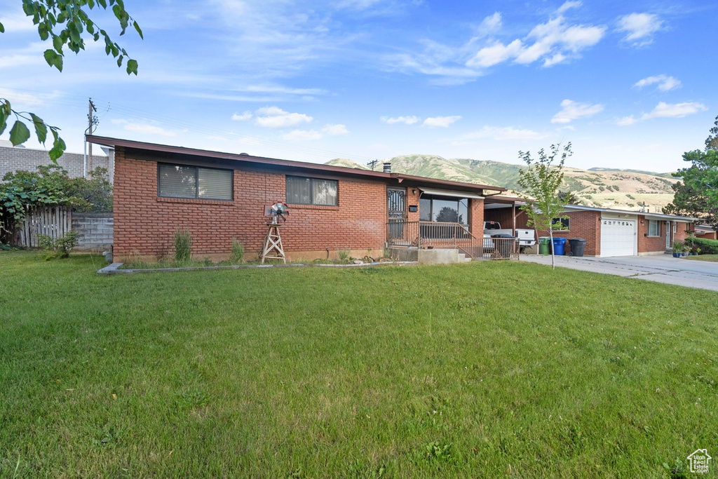 View of front of home with brick siding, a garage, driveway, a front yard, and a mountain view