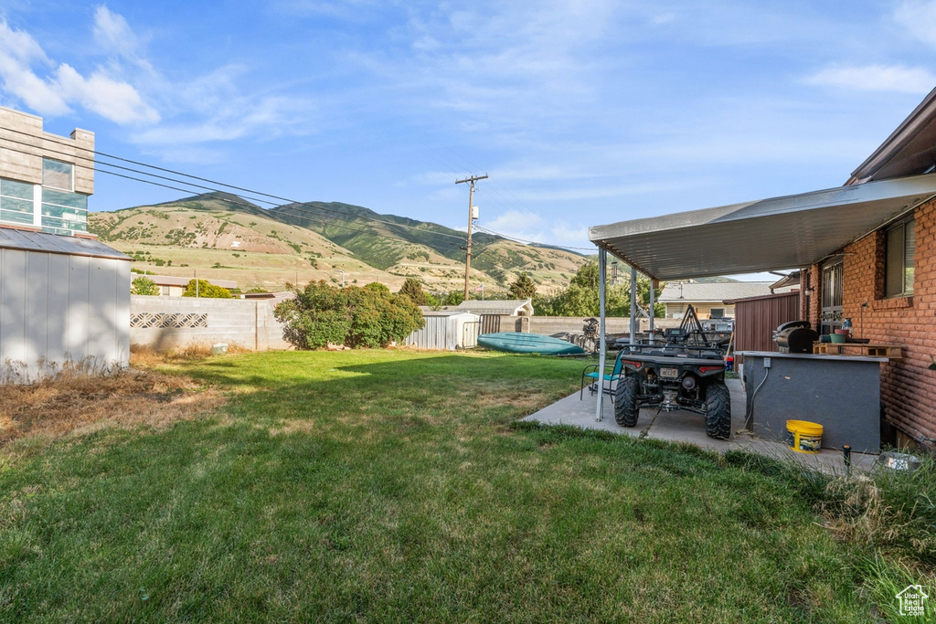 Fenced backyard with a storage shed, a mountain view, and a patio