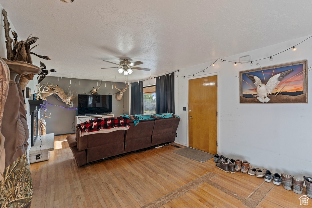 Living area with hardwood / wood-style flooring, ceiling fan, and a textured ceiling