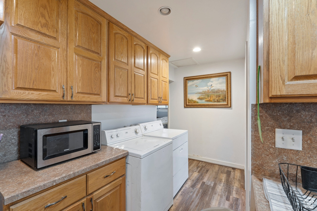 Laundry area with independent washer and dryer, wood finished floors, and recessed lighting