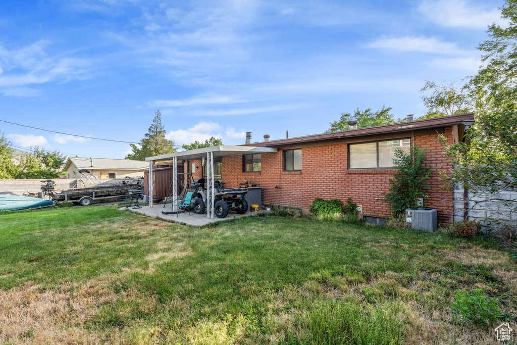 Back of house featuring brick siding, a lawn, and a patio