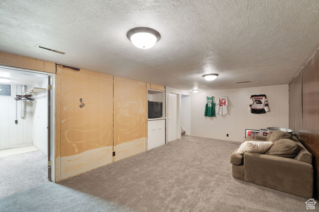Carpeted living area with a textured ceiling and stairway