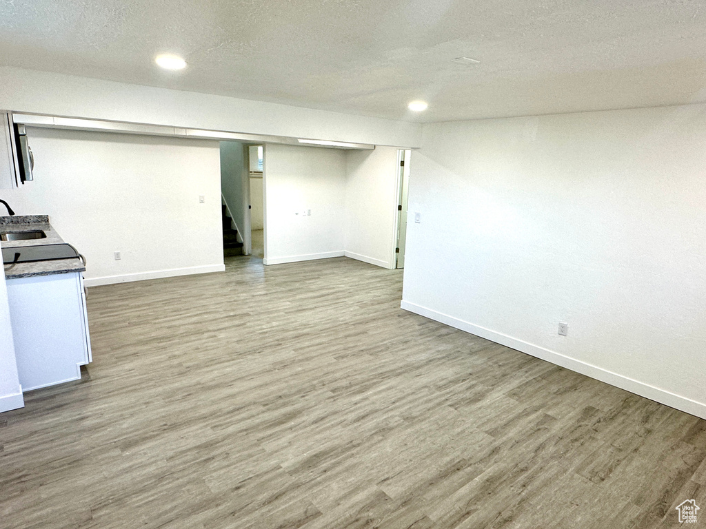 Finished below grade area featuring stairway, wood finished floors, a textured ceiling, and recessed lighting