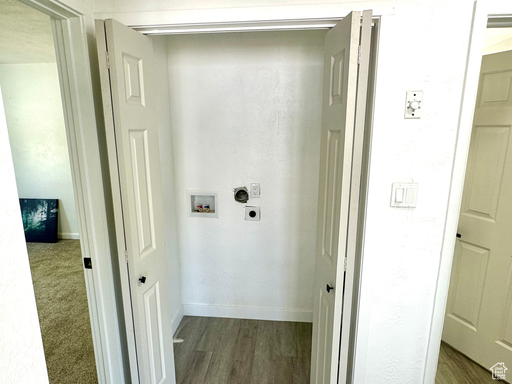Laundry area with hookup for an electric dryer, hookup for a washing machine, and wood finished floors