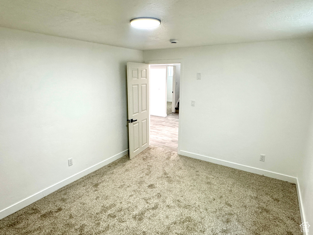 Empty room featuring light colored carpet and a smoke detector