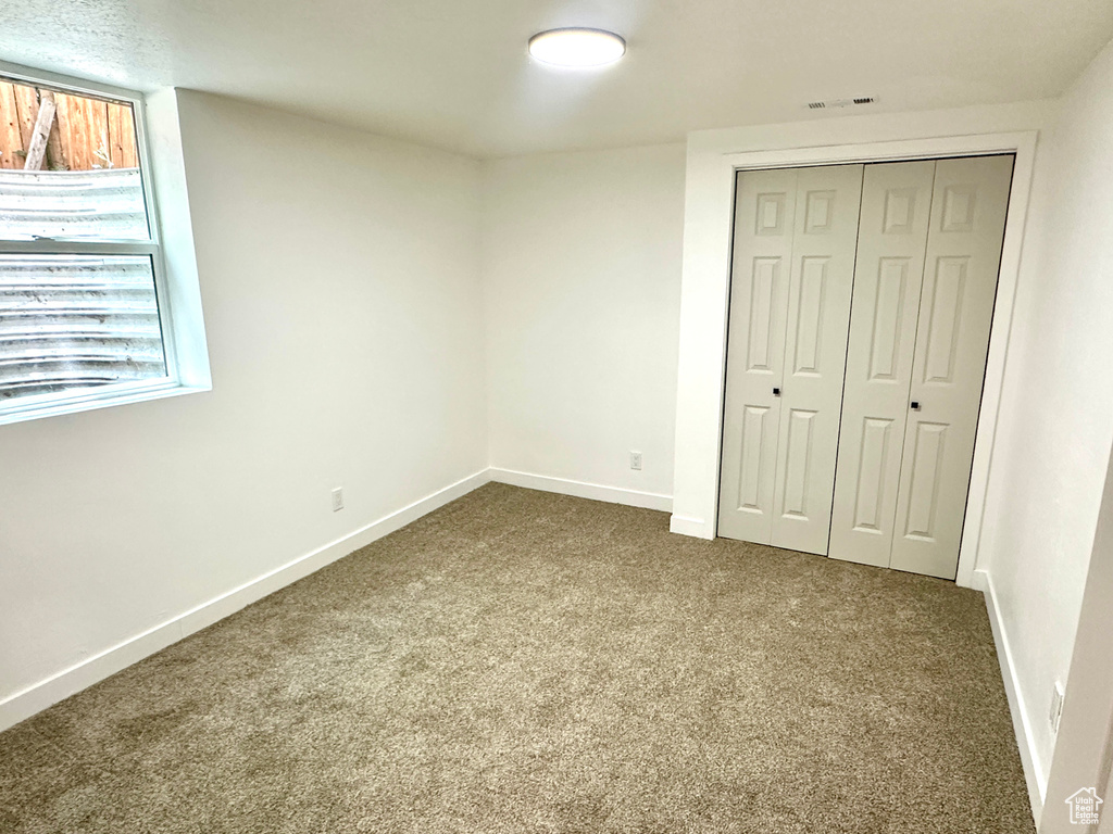 Unfurnished bedroom with dark carpet, a closet, and multiple windows