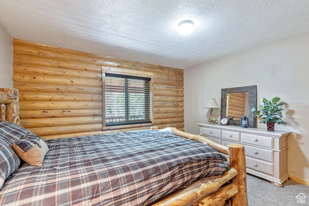 Bedroom featuring log walls, a textured ceiling, and light colored carpet